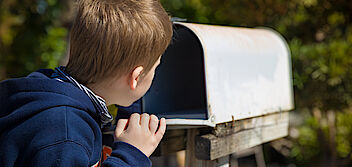 JPG: Junge schaut in leeren Briefkasten