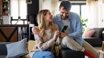 SWU Paar Lachend am Handy auf Sofa